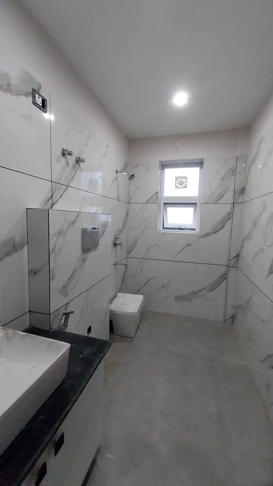 Bathroom with large marble-finish tiles and wall-hung WC