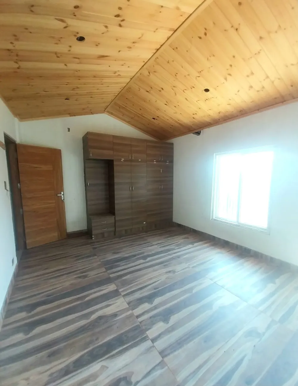 Attic bedroom with pine ceiling, wardrobe and wood-finish floor